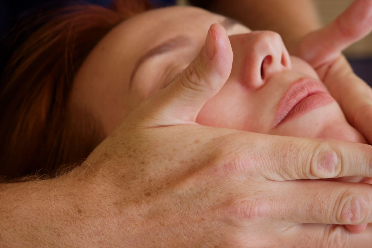 Mani che massaggiano delicatamente il viso durante un lifting facciale naturale